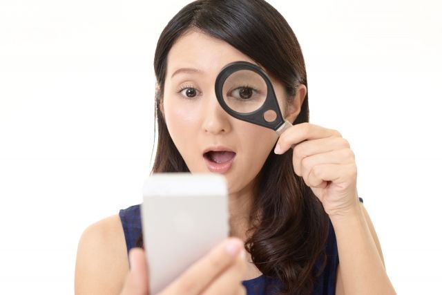 スマホと虫めがねで探す女性